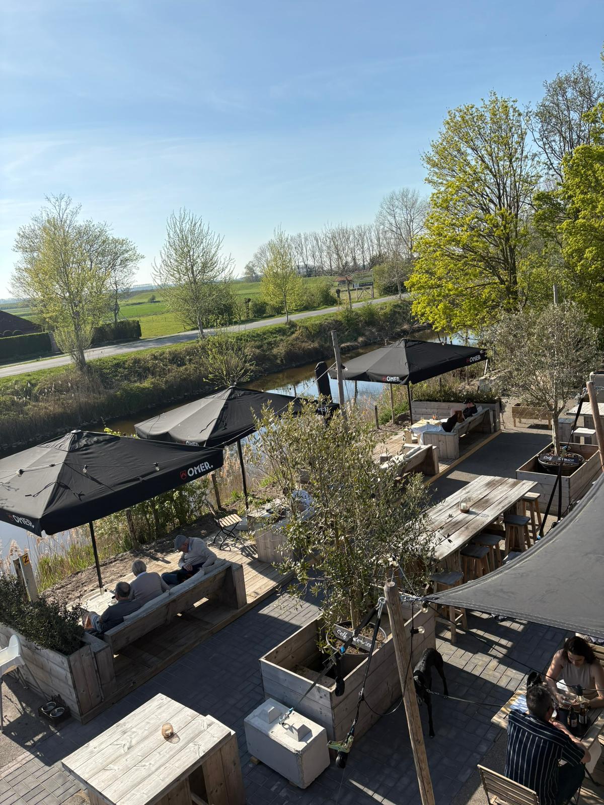 Terras van bovenaf langs het water met loungebanken