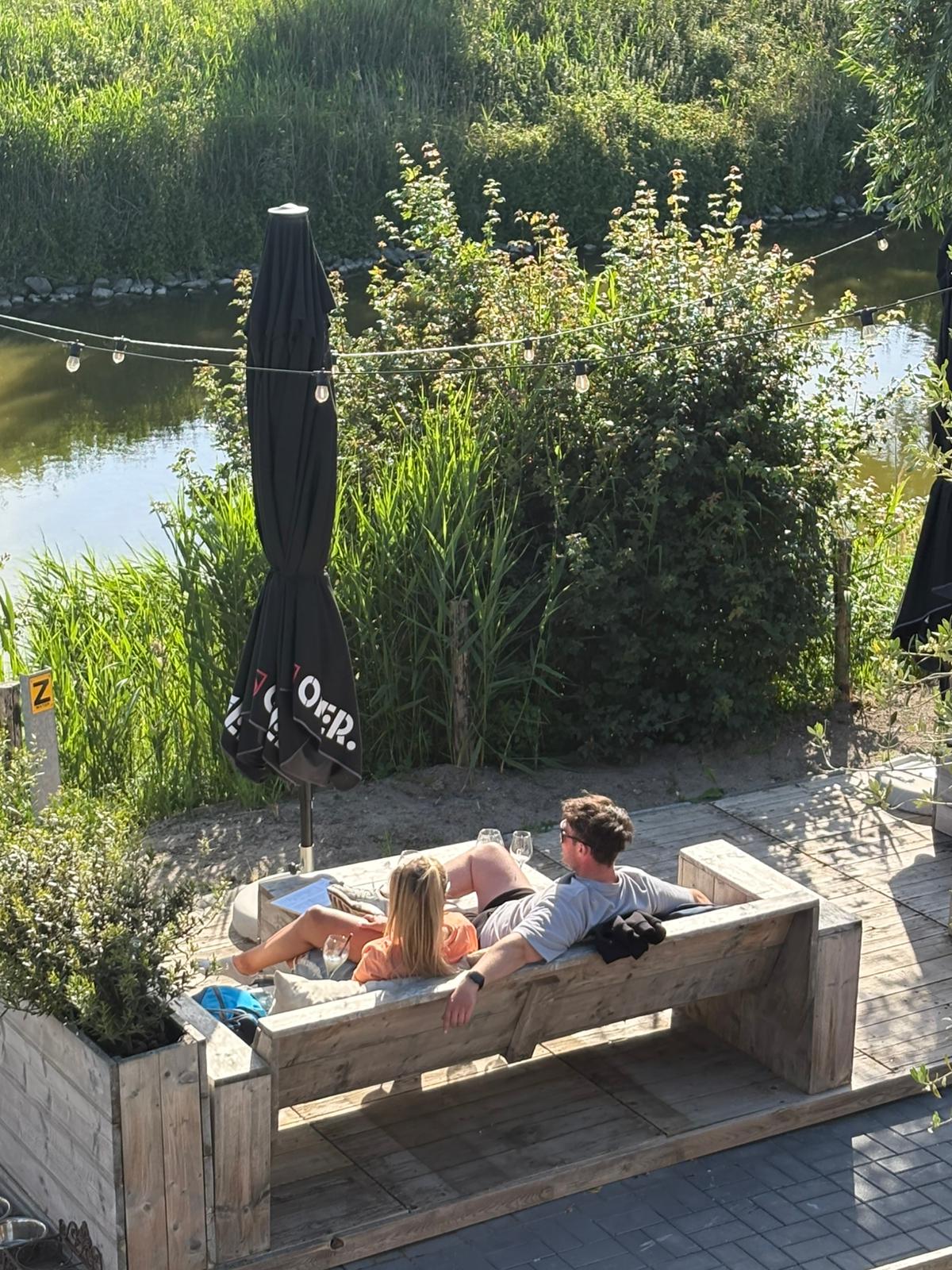 Gasten ontspannen op de loungebank aan het water